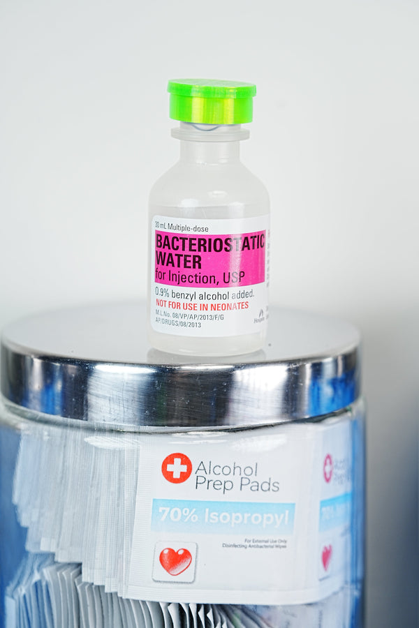 Best 1 mL insulin syringes for peptide and GLP-1 injections — Hospira BAC water bottle on a jar of 70% isopropyl alcohol prep pads, ready for sterile injection prep