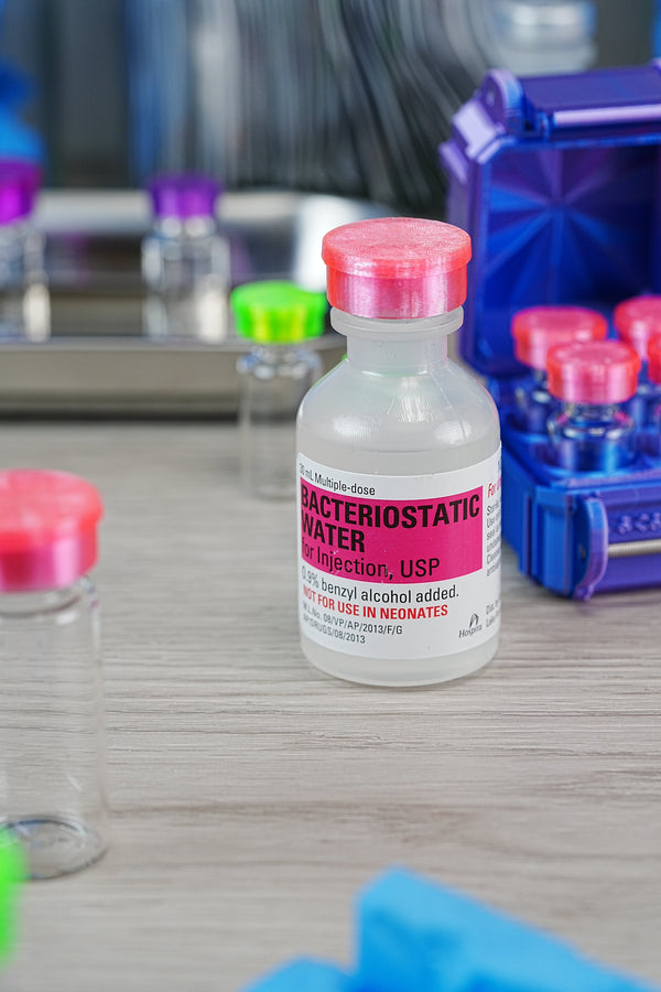 Buy bacteriostatic water on Amazon — Hospira BAC water bottle USP label visible alongside a hard-shell VialCase with pink-capped peptide vials