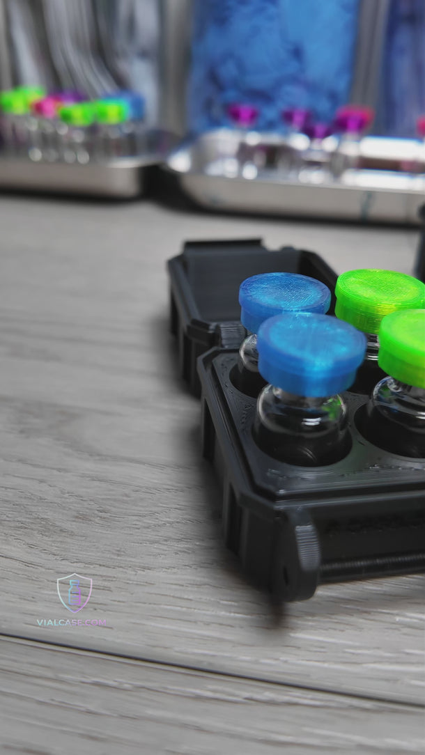 Two small black hard-shell storage cases are shown being closed and stacked on top of each other. Hands adjust and hold the cases, demonstrating their compact size and secure design. The cases sit on a clean surface with medical supplies in the background.